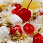 Marshmallow salad is a colorful combination of marshmallows, shredded coconut, whipped cream, sour cream, mandarin oranges, and fresh cherries, pineapple, and other toppings of your choice.